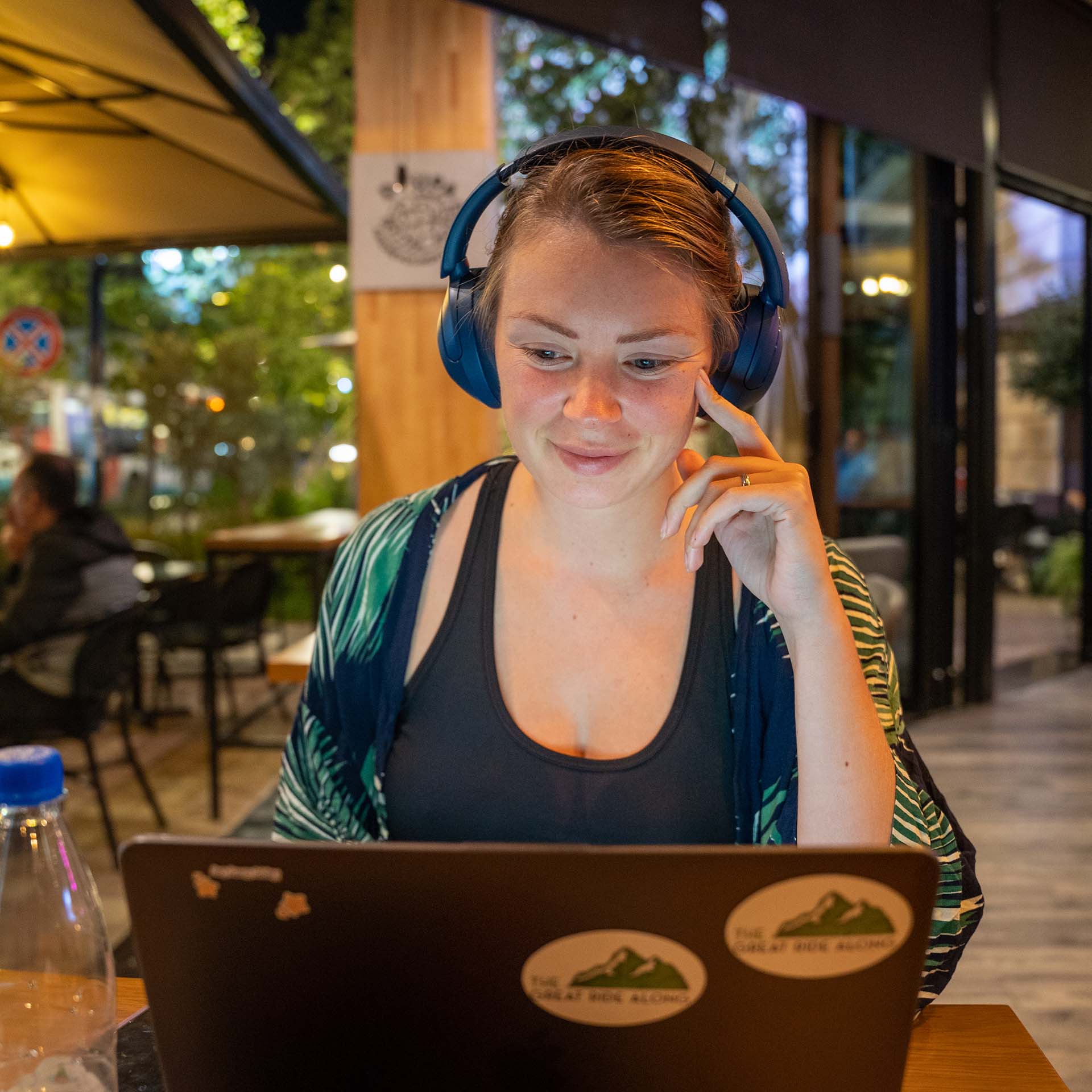 Nadia in een cafe met koptelefoon op aan het werk op haar laptop